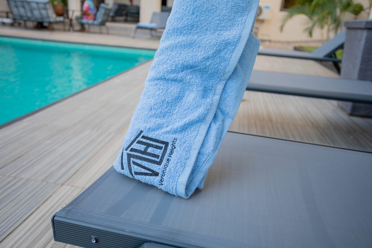 Branded Veronique Heights towel on a poolside lounger